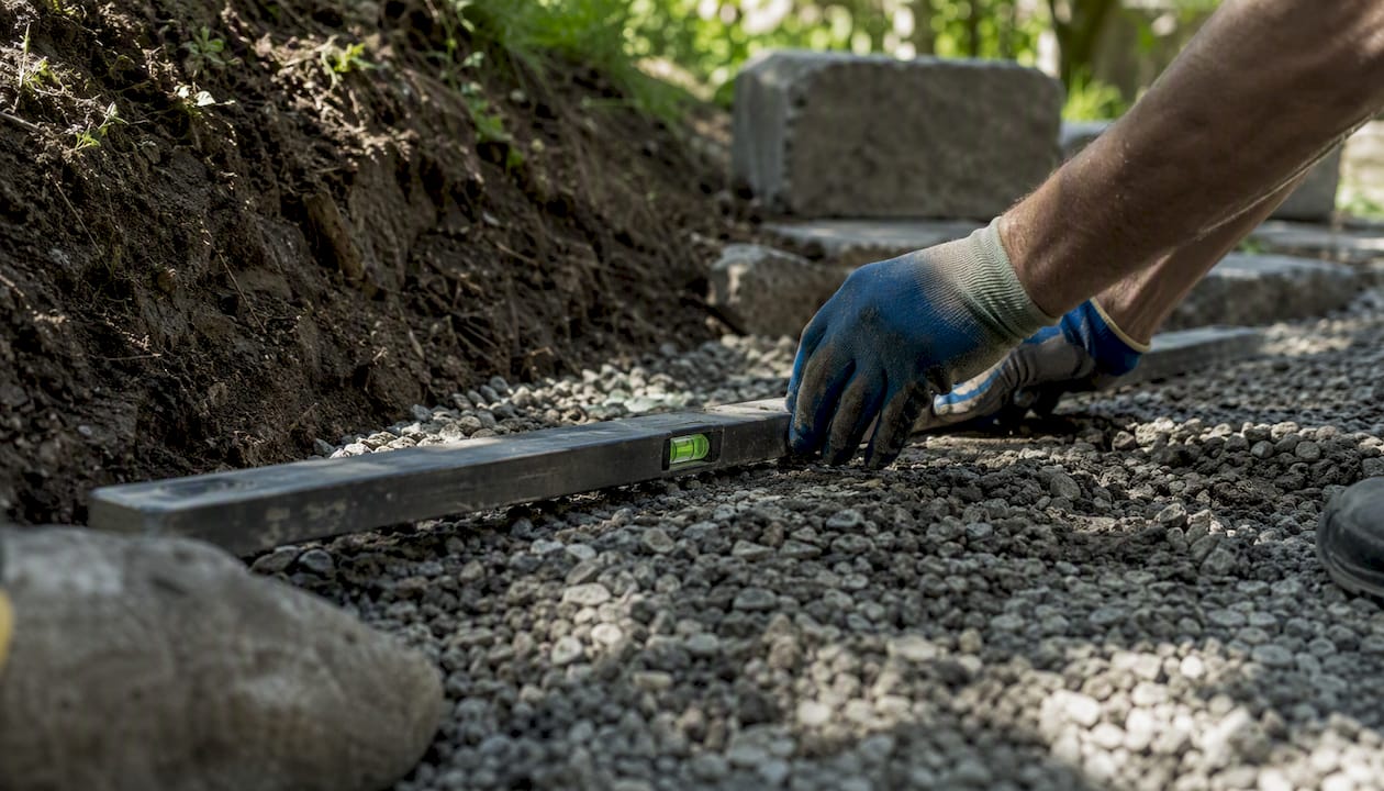 Close-up of hands compacting gravel for retaining wall