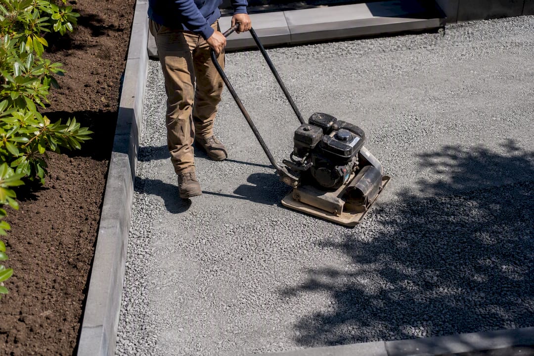 Compacting gravel patio base in layers with plate compactor