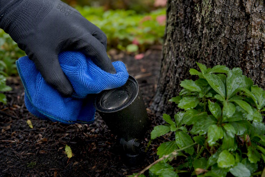 Gloved hand cleaning outdoor light lens